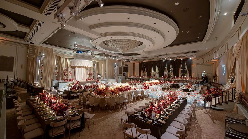 Hotel ballroom with a domed ceiling, set with long tables and red floral centerpieces