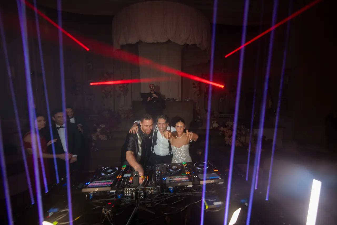 A DJ booth beneath a curtain of blue and red laser beams