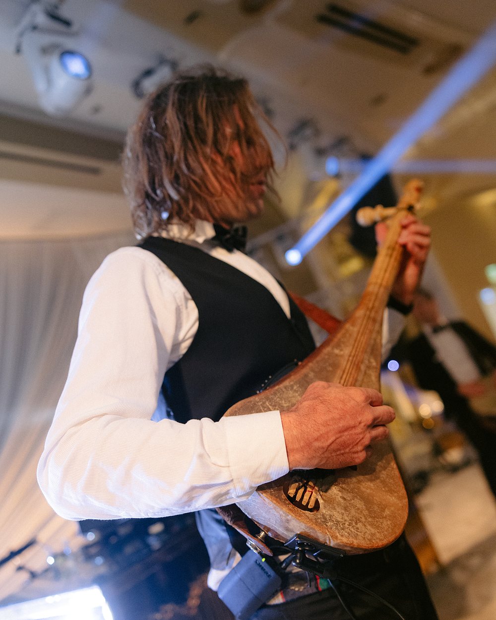 A musician playing a long-necked fretted lute of the bouzouki family at a reception