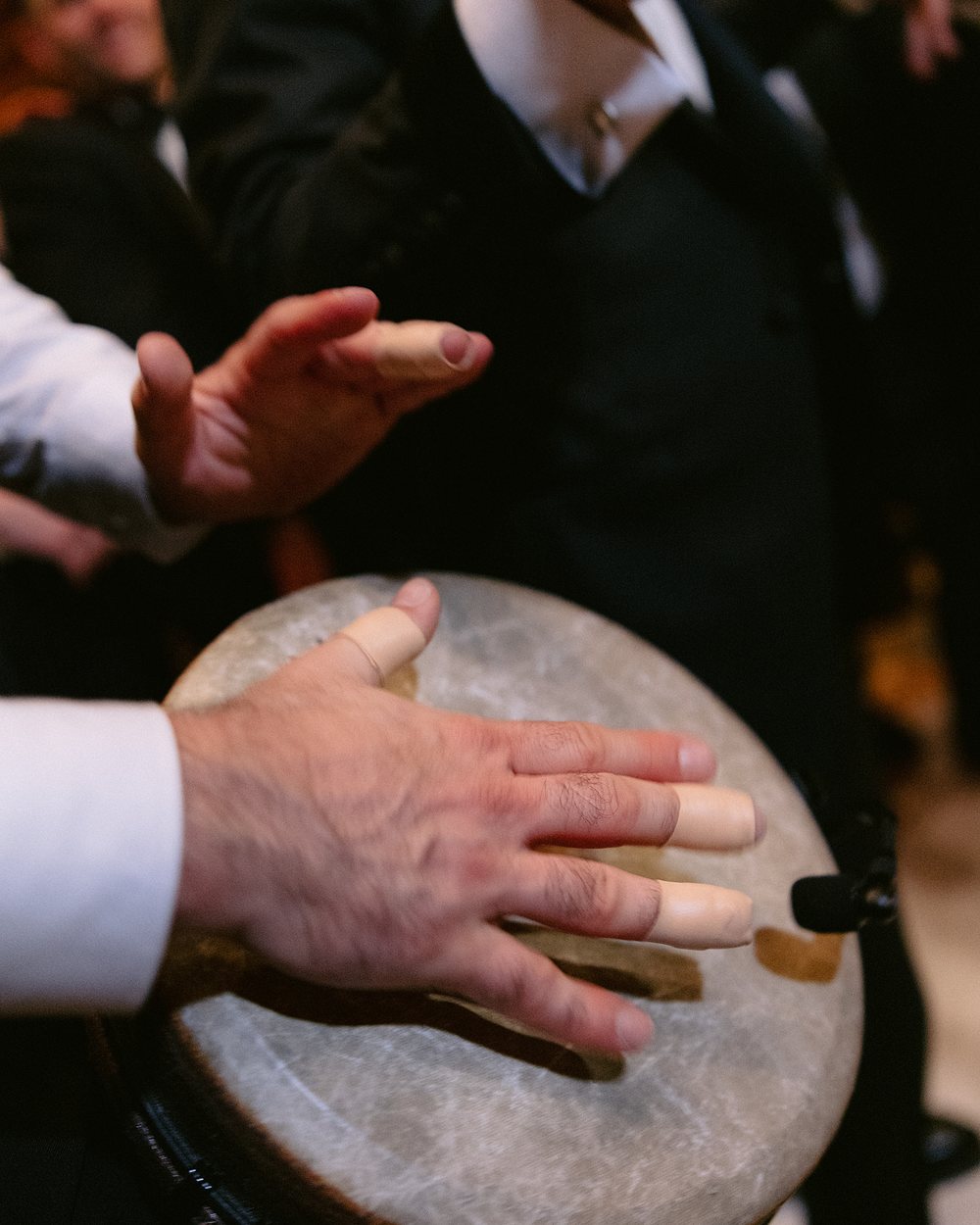 Close view of a percussionist's hands playing the head of a large frame drum