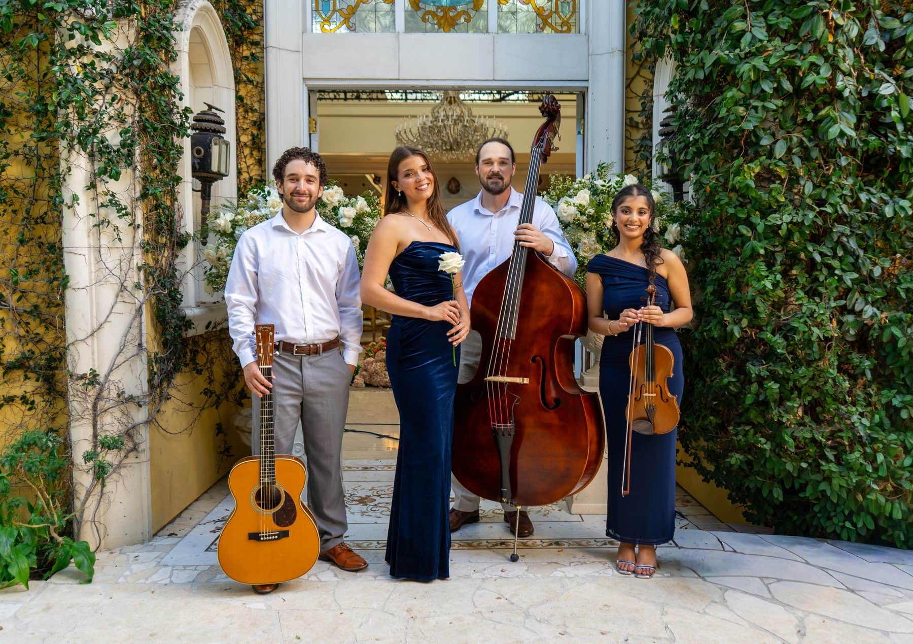 An acoustic ensemble with guitar, upright bass and cello playing in a garden