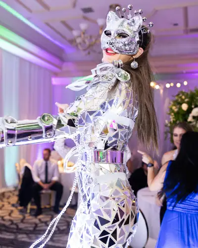 A performer in a mirrored mosaic costume and jewelled mask on a ballroom floor.
