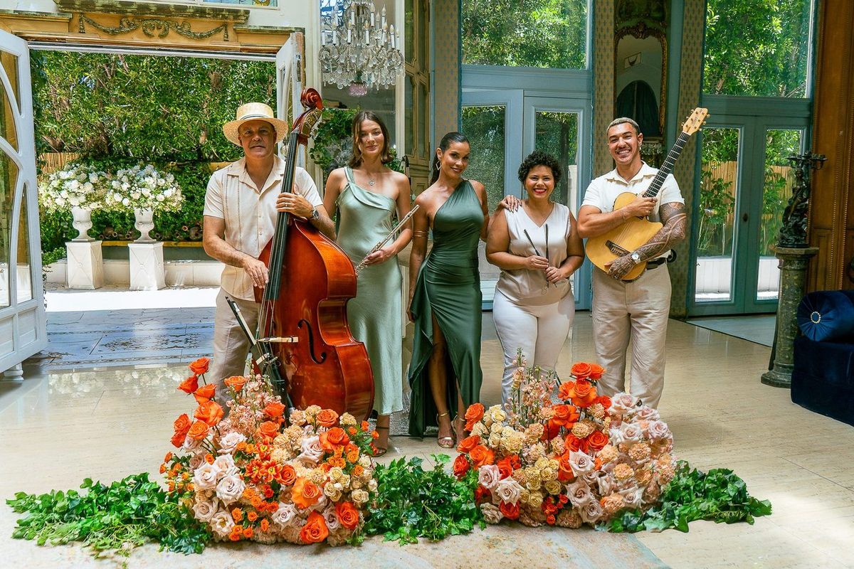 Janeiro performing beside a bank of flowers at a garden event