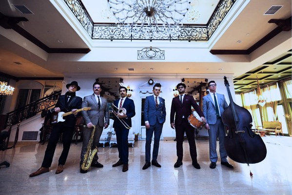 Mood's seven members in suits in a bright marble hall, with guitar, sax, trombone, snare and upright bass