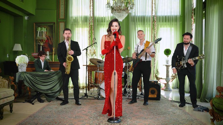 LIV Vintage's singer in a red sequinned gown at the mic, with sax, keys, drums and two guitars in a green-curtained room