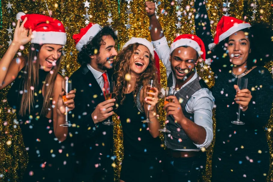 Guests in Santa hats toasting at a holiday party