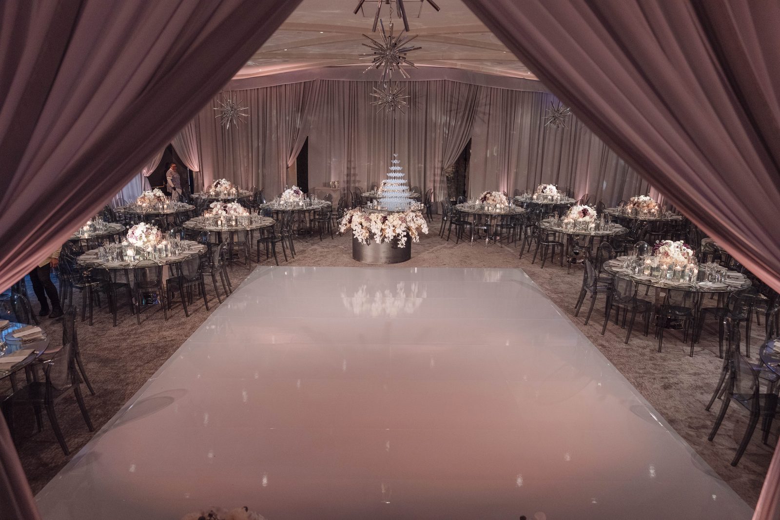 View framed between drape panels down the white dance floor at Hotel Bel-Air towards the wedding cake