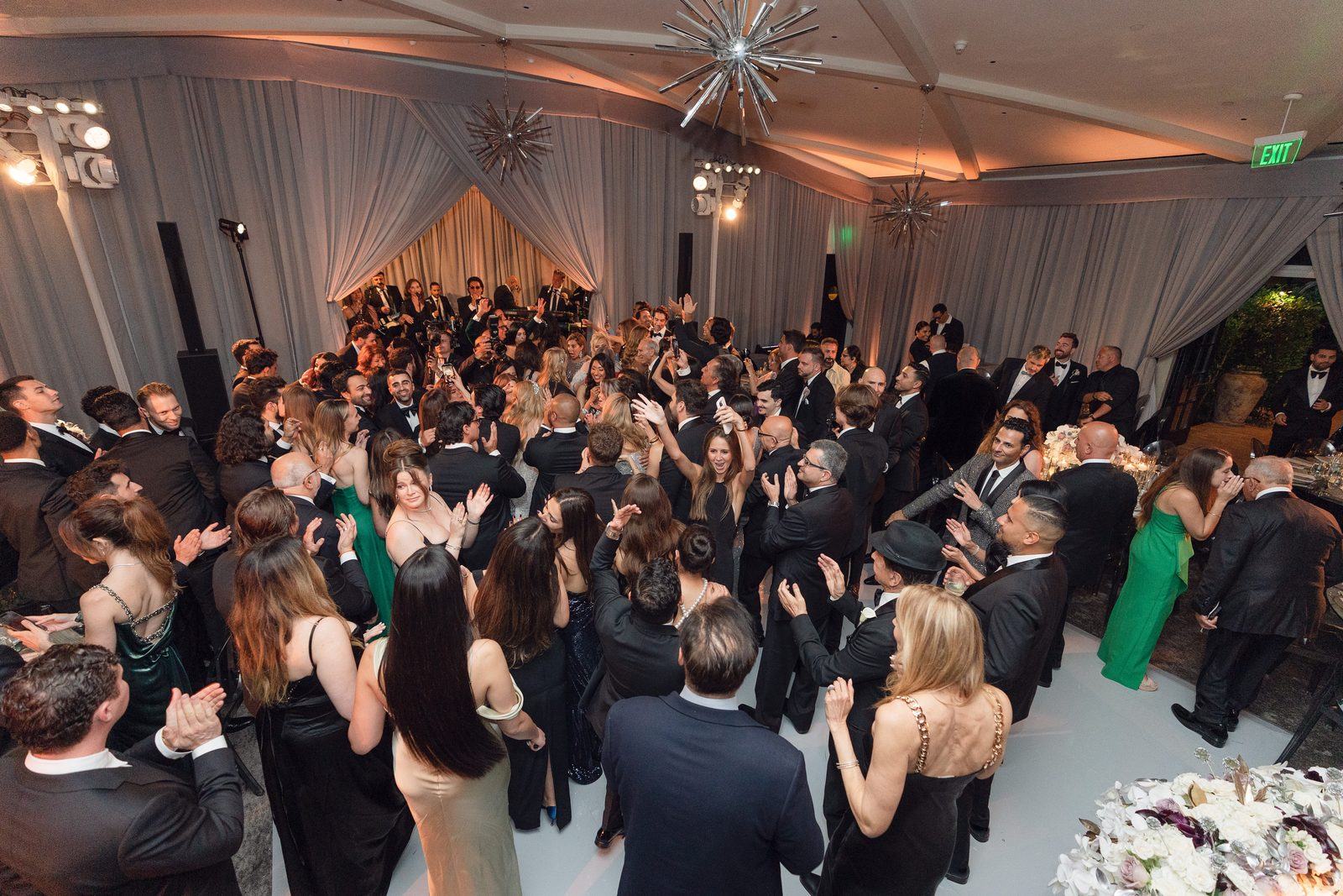 Guests filling the white dance floor at Hotel Bel-Air under warm uplighting and starburst chandeliers