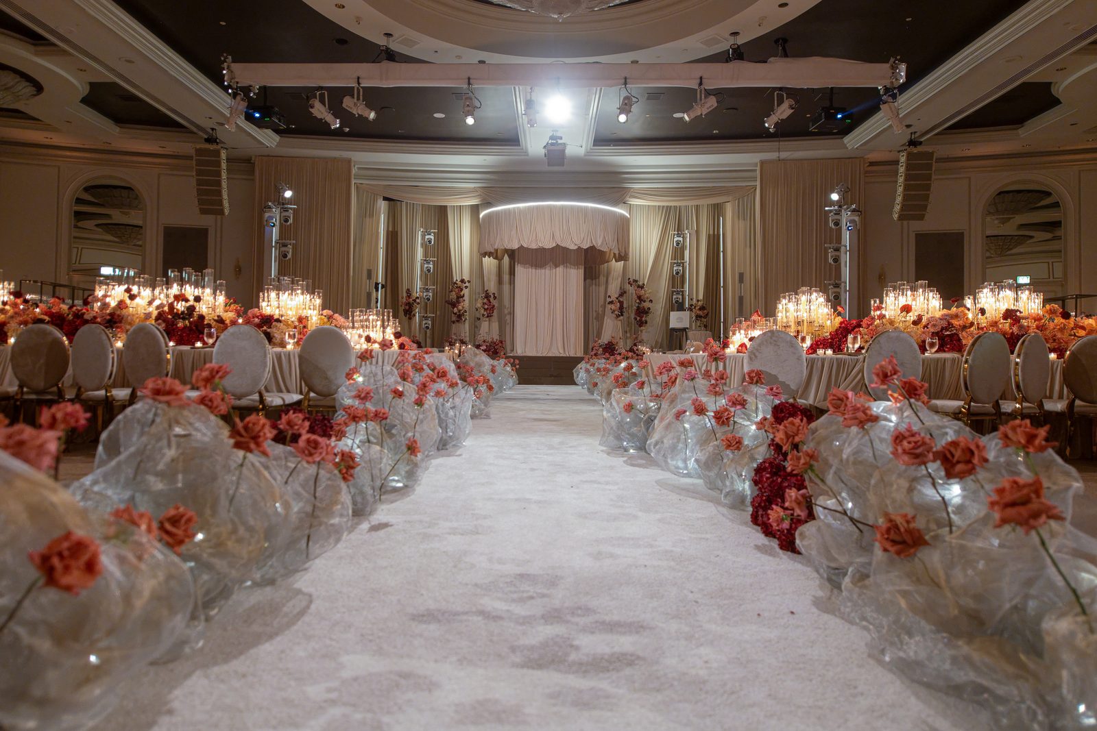 Floral-lined aisle running towards the draped stage in the Beverly Wilshire ballroom