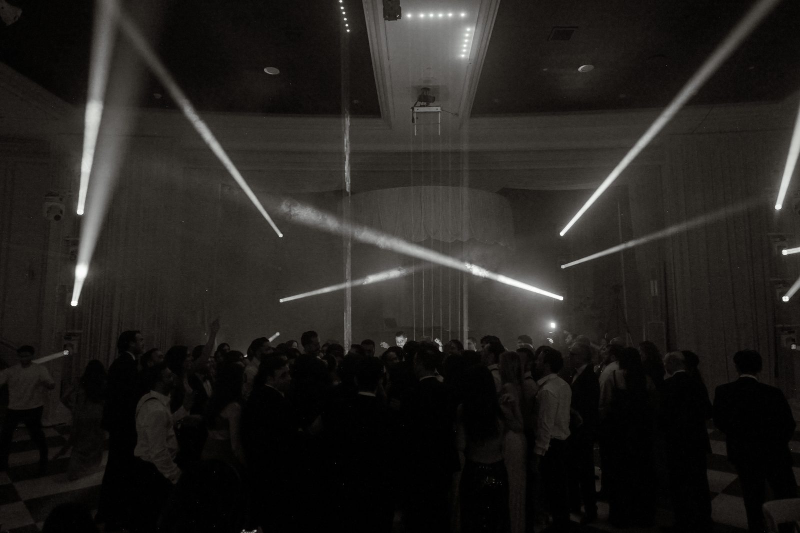 Beams of light crossing over a packed dance floor at the Beverly Wilshire, in black and white
