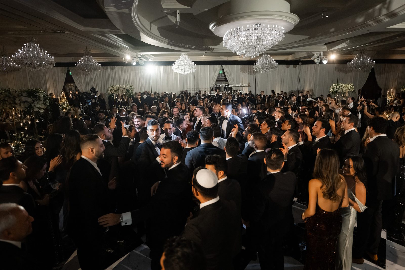Wide view of a packed ballroom at the Four Seasons Westlake Village under several crystal chandeliers