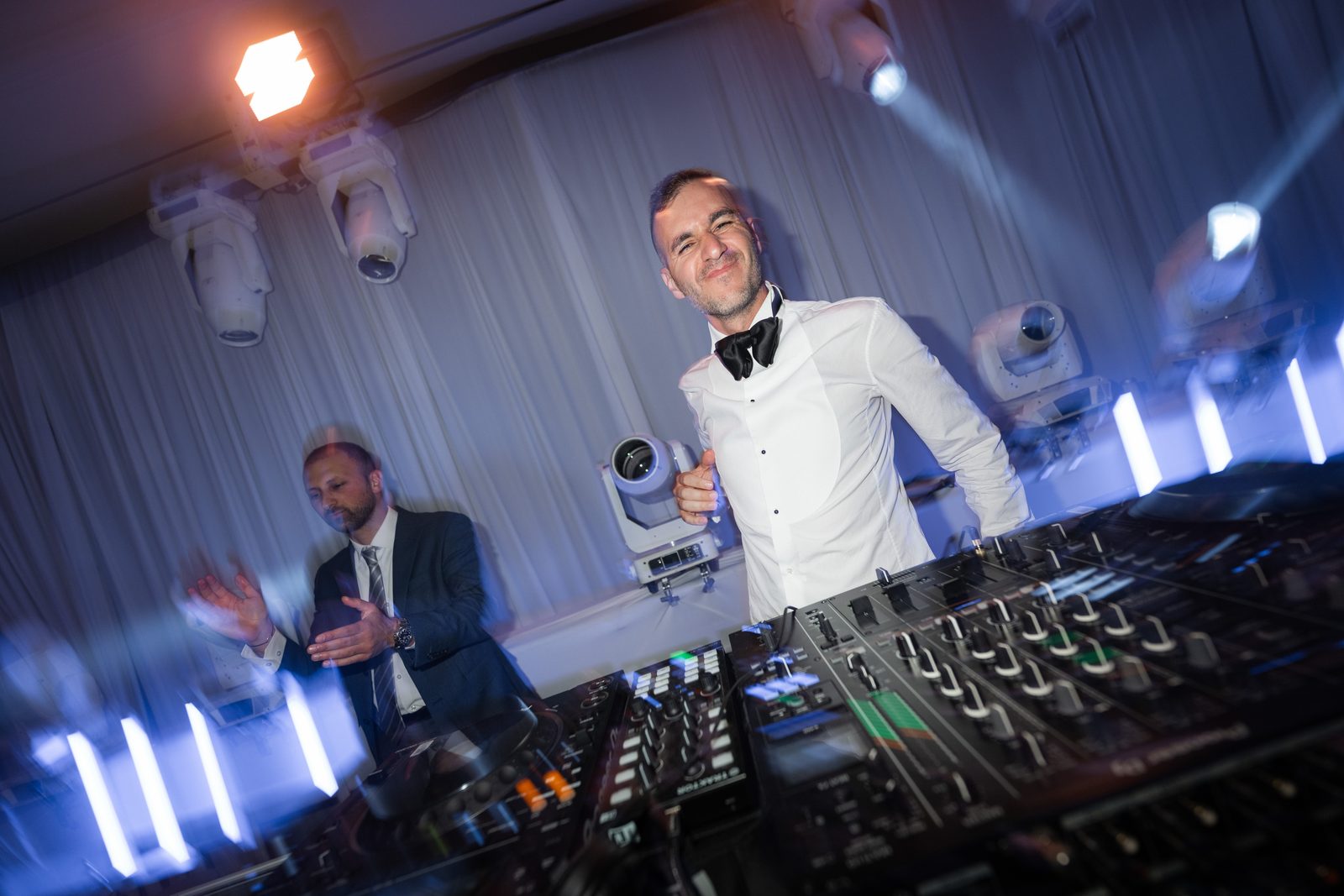 DJ smiling behind the mixer at the Four Seasons Westlake Village under blue beams and vertical LED battens
