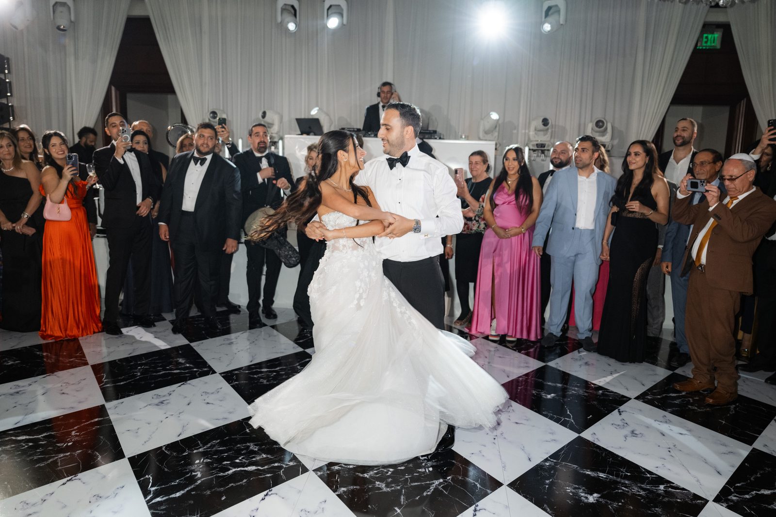 Couple dancing alone on the black and white marble floor at a Four Seasons Westlake Village wedding while guests watch from the edge
