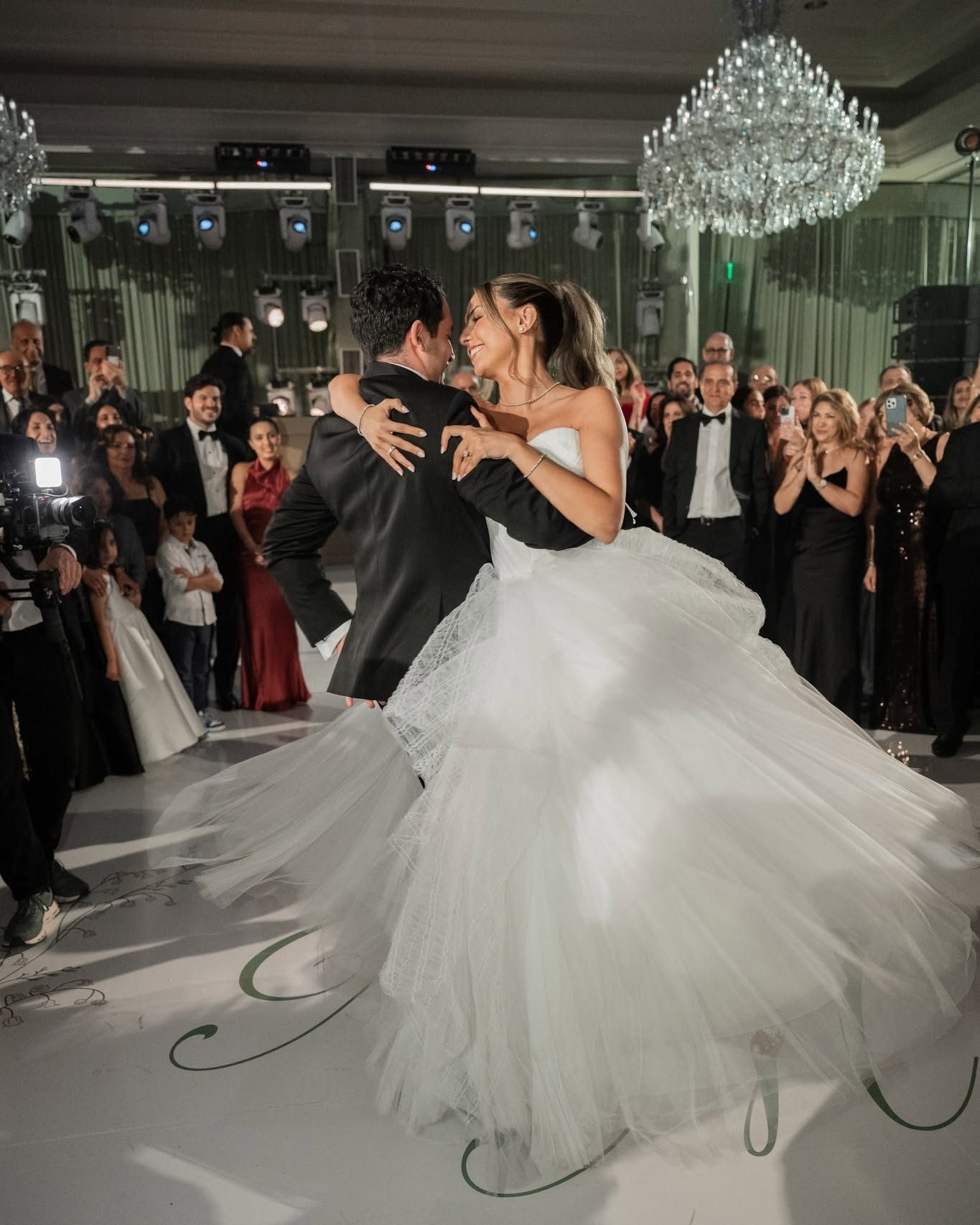 Couple turning together on a white monogrammed dance floor at the Four Seasons Westlake Village with mirrored walls behind them