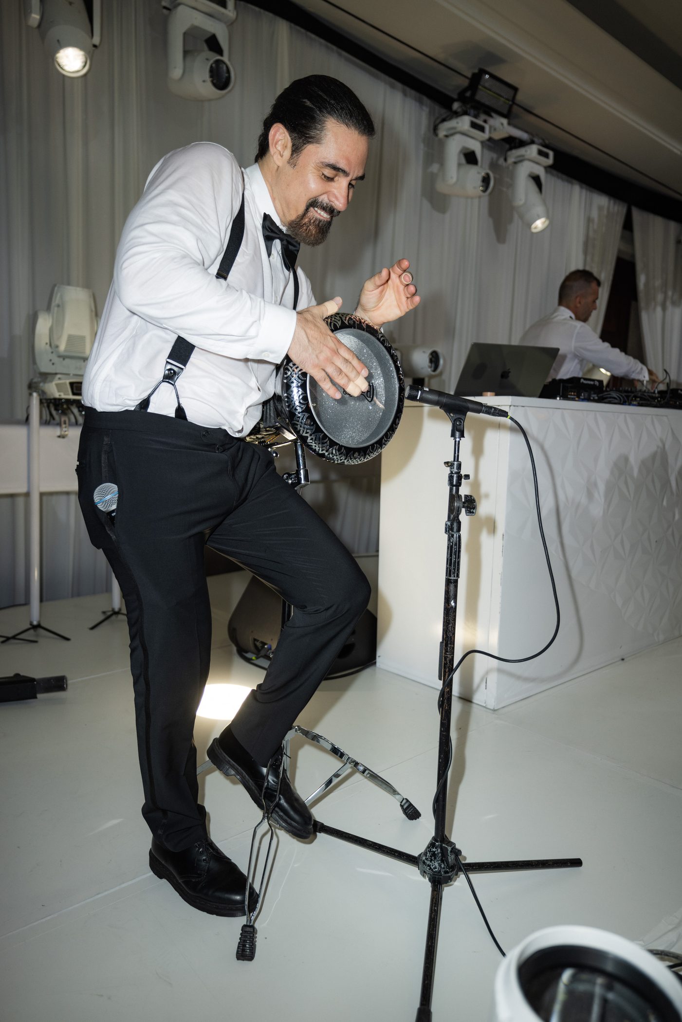 Percussionist playing a frame drum into a microphone beside the DJ booth at a Four Seasons Westlake Village wedding