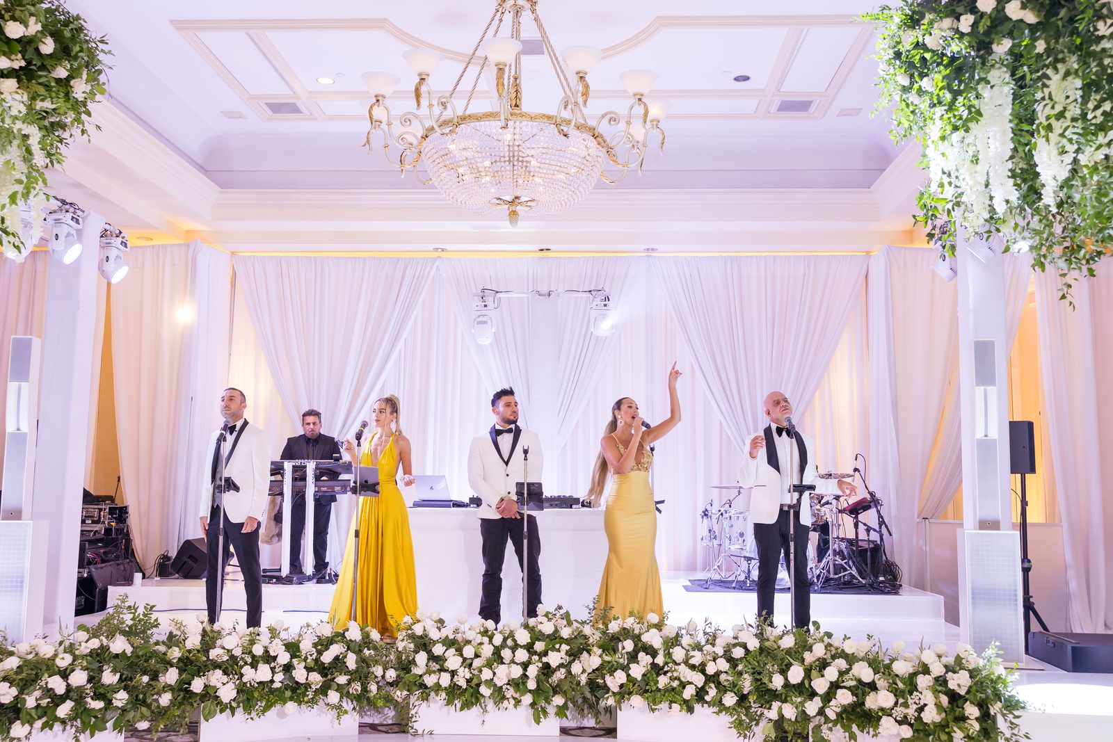 Six-piece live band with two vocalists in yellow gowns performing on the white stage at Waldorf Astoria Monarch Beach