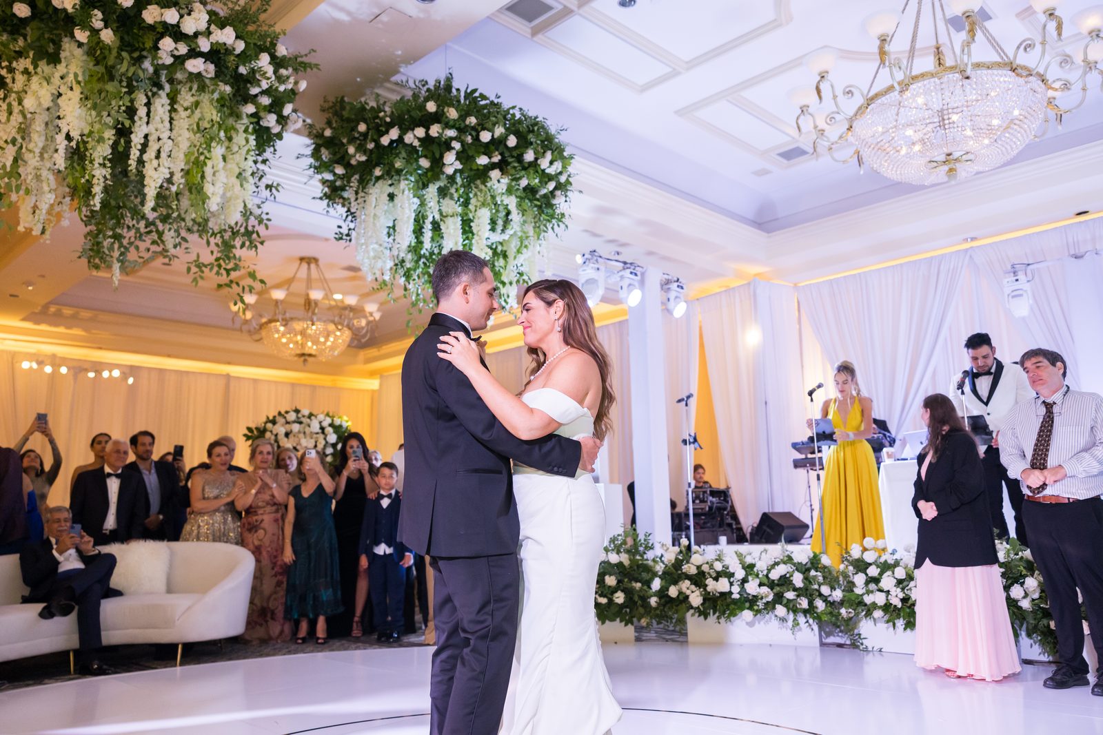 Couple dancing beneath suspended white floral and greenery installations at Waldorf Astoria Monarch Beach